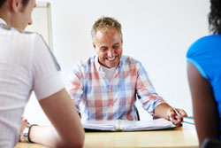 A teacher smiling at an assignment from two students